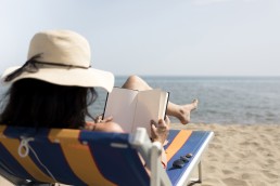 mujer leyendo un libro sobre tecnología en la playa